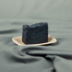 Handmade natural soap bar with activated charcoal on a ceramic dish