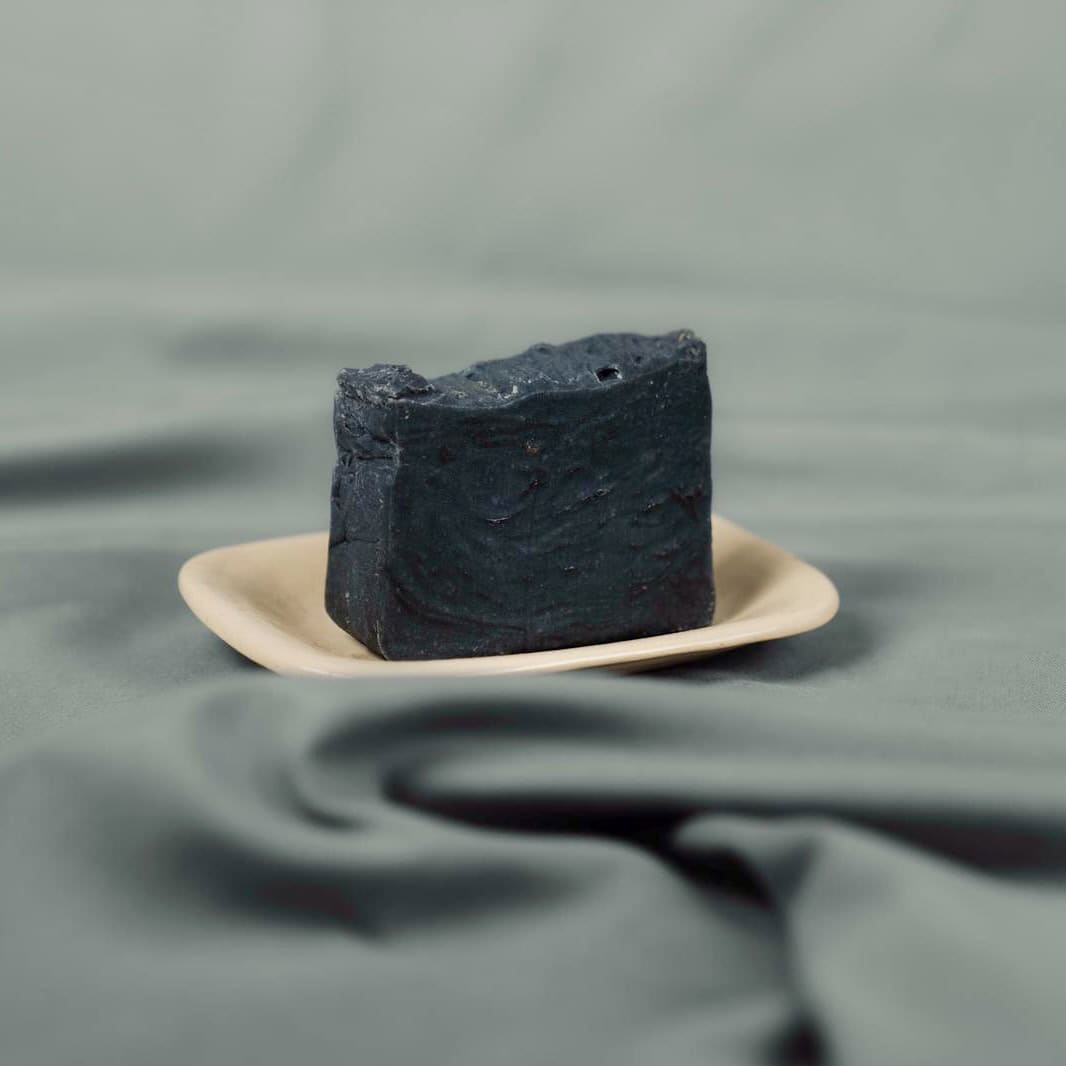 Handmade natural soap bar with activated charcoal on a ceramic dish