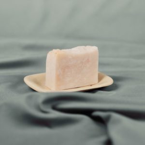 Handmade natural soap bar with soft pink on a ceramic dish
