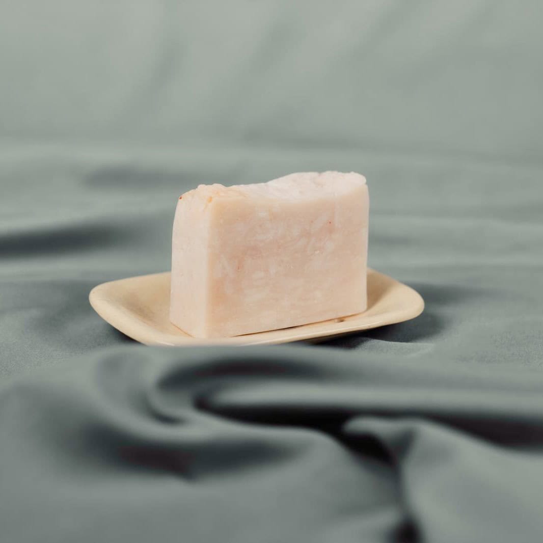 Handmade natural soap bar with soft pink on a ceramic dish