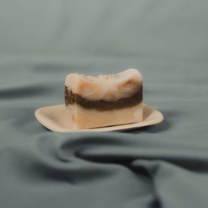 Handmade natural soap bar with brown stripe on a ceramic dish
