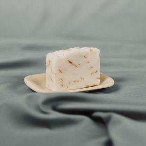 Handmade natural soap bar with calendula petals on a ceramic dish