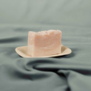 Handmade natural soap bar with soft pink swirl on a ceramic dish