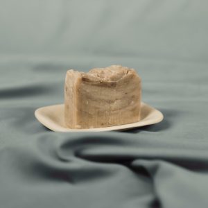 Handmade natural soap bar with brown clay on a ceramic dish